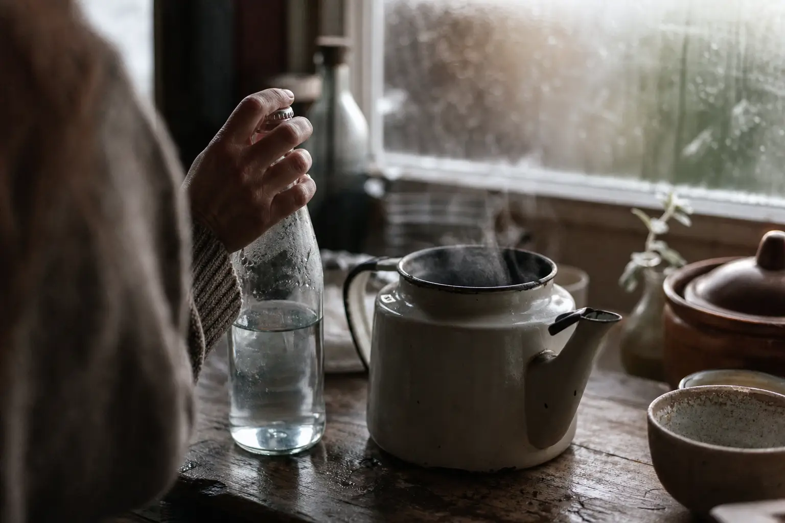 Steife Hand greift morgens nach einer Wasserflasche in der Küche